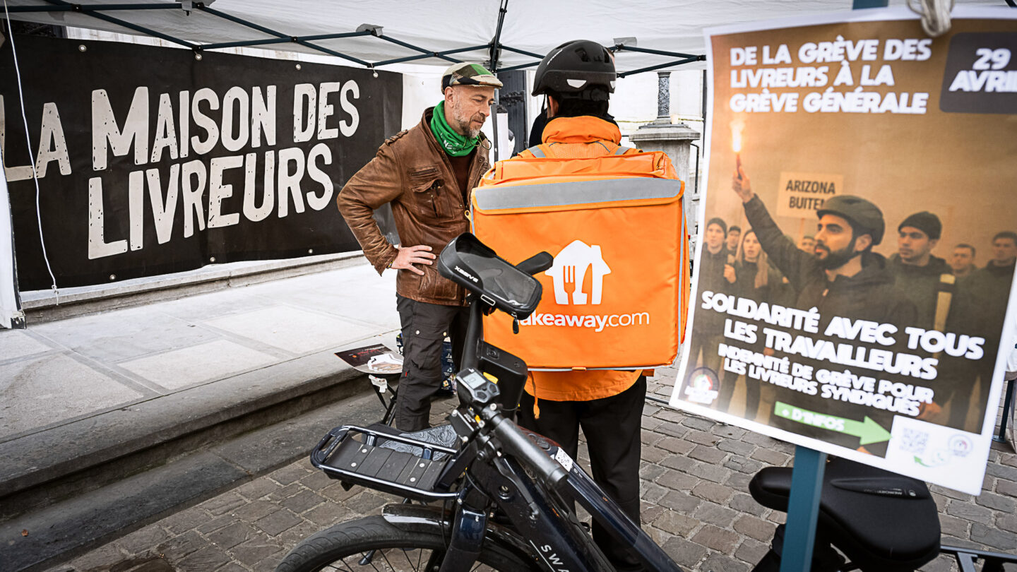 Un livreur discute avec un syndicaliste à un stand de la Maison des livreurs de Bruxelles