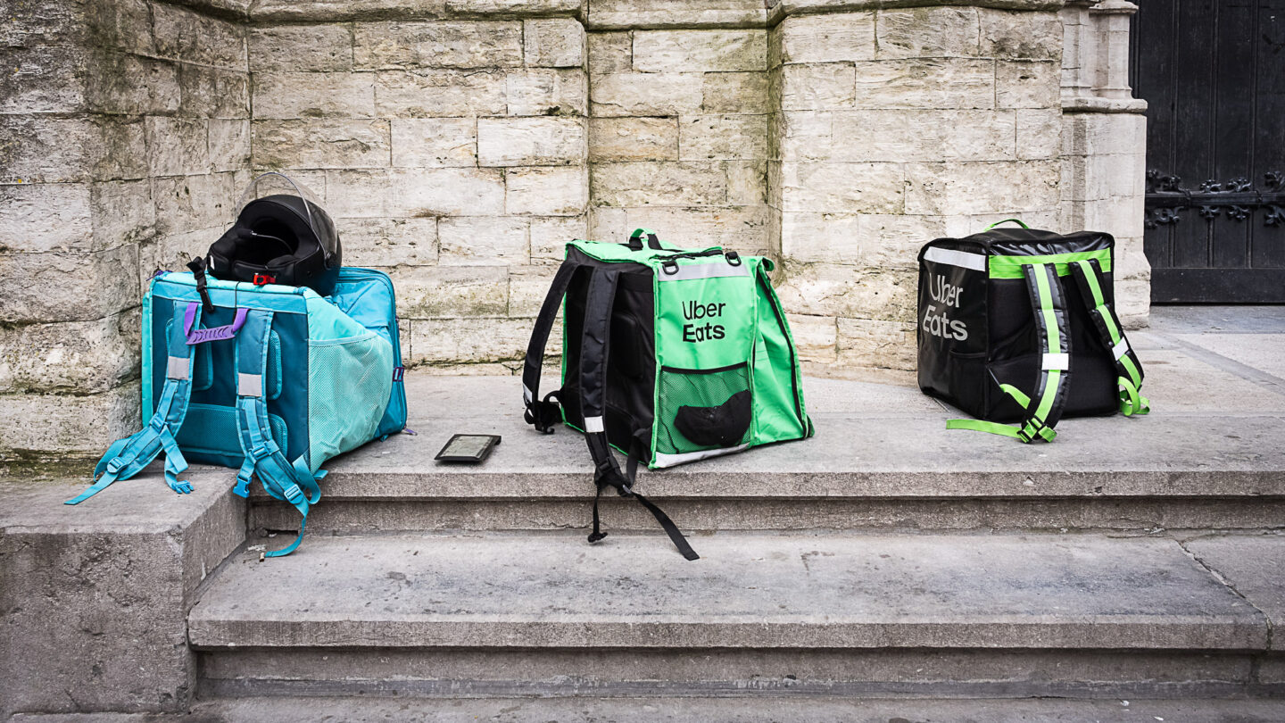 Des sacs de livreurs à vélo sont alignés sur le parvis d'une église.