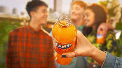 Un main tient une bouteille de Fanta, une boisson couleur orange.