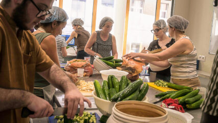 Au centre de l'image, Christine Marchand, bénévole, découpe des légumes, entourée d'autres bénévoles.