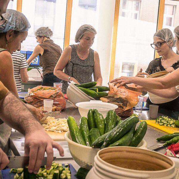 Au centre de l'image, Christine Marchand, bénévole, découpe des légumes, entourée d'autres bénévoles.