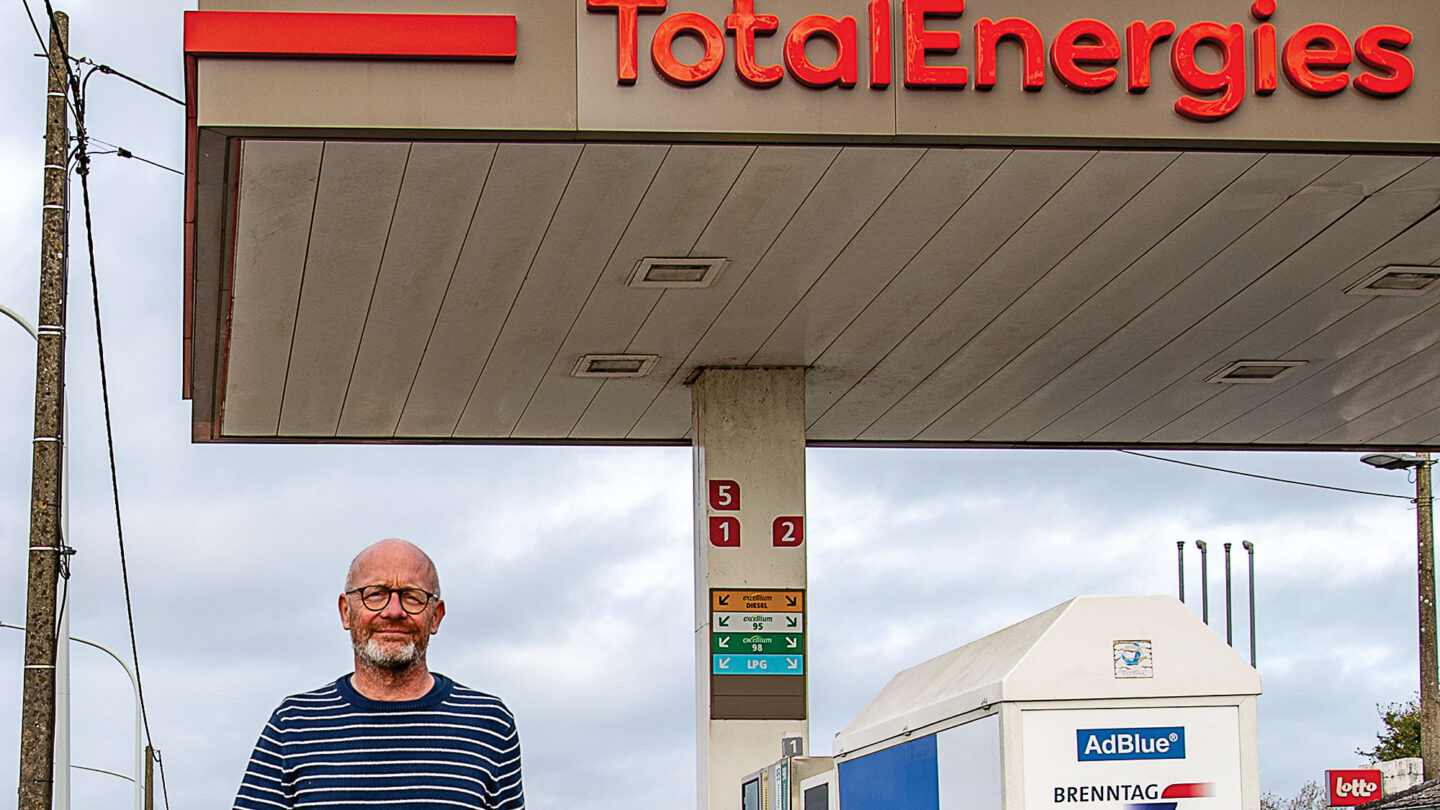 Hugues Falys marche devant une pompe essence TotalEnergies.