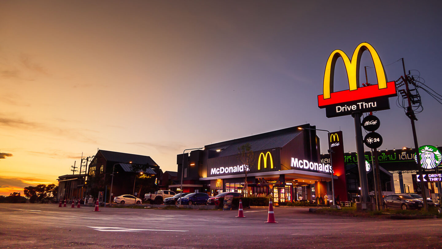 Devanture de McDonald's avec le logo qui brille dans le soleil couchant.