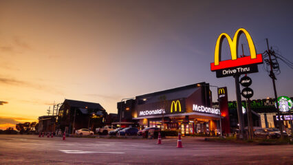 Devanture de McDonald's avec le logo qui brille dans le soleil couchant.