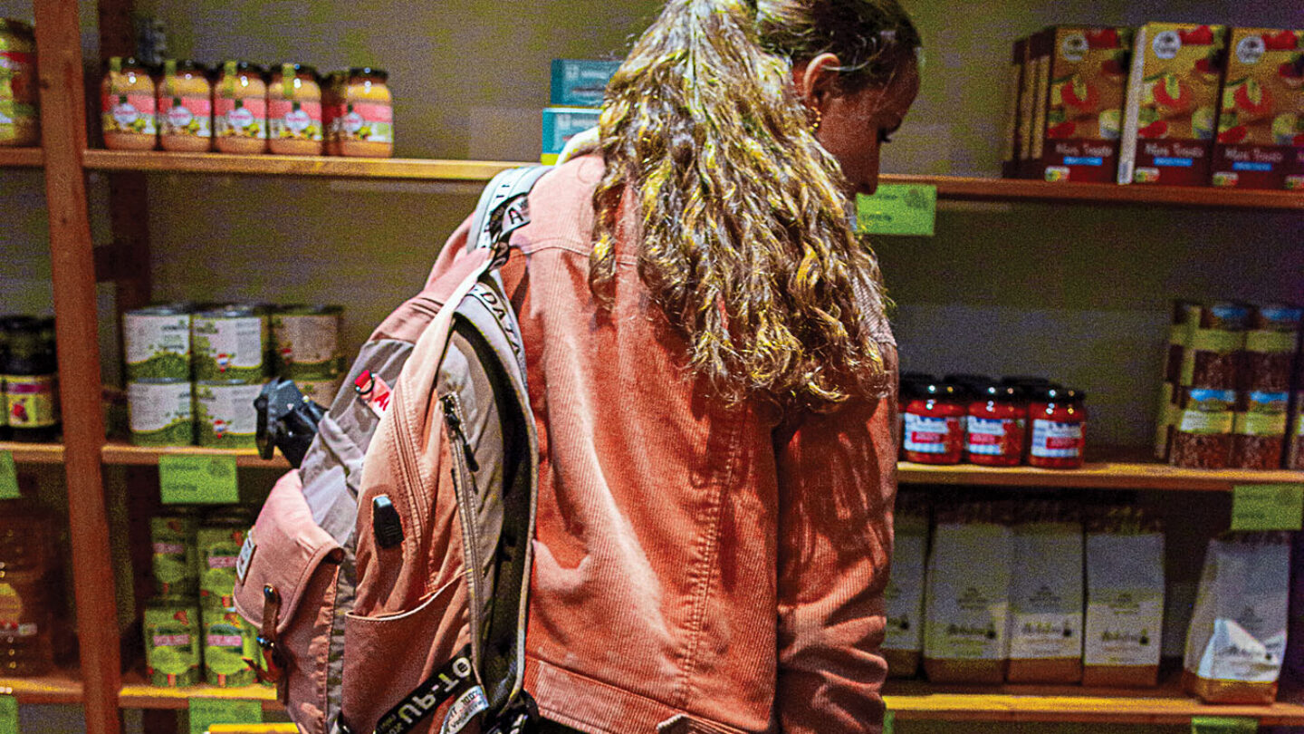 Une femme, vue de dos, fait ses courses dans une épicerie sociale.