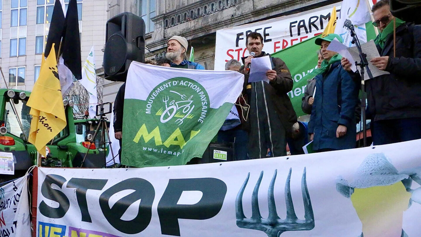 Des manifestants hissent un drapeau du Mouvement d'action paysanne et des calicots contre les accords de libre-échange.