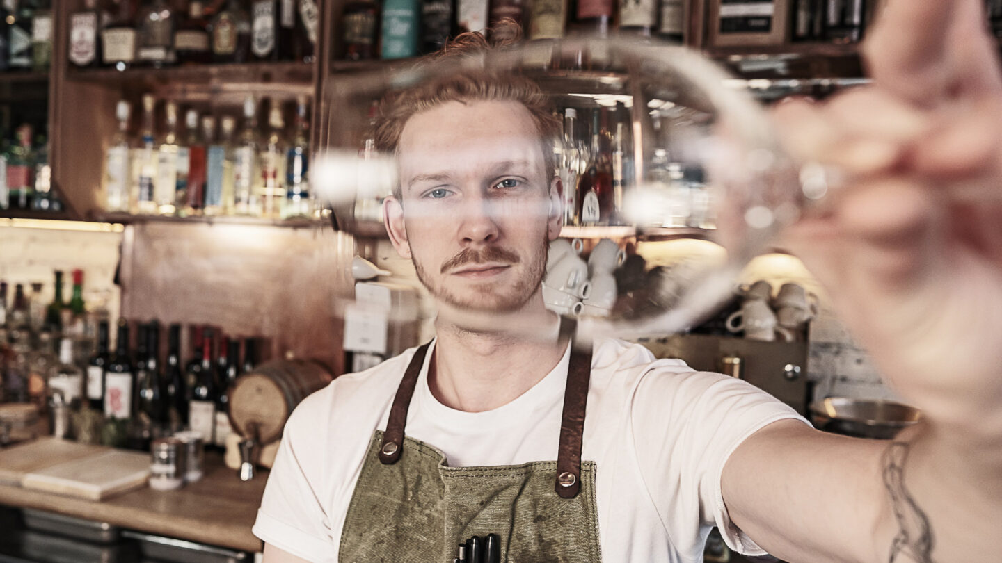 Young redhead barman working at the bar